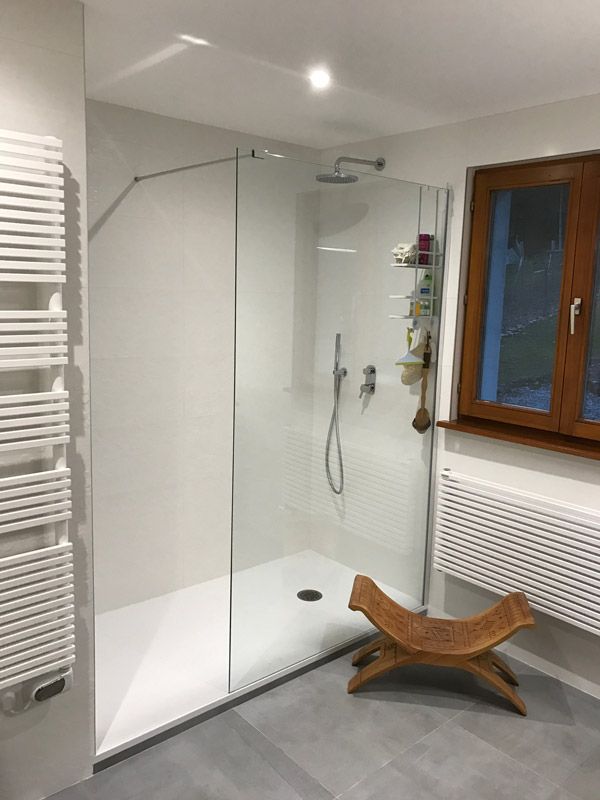 Une salle de bain avec douche à l'italienne et banc en bois.