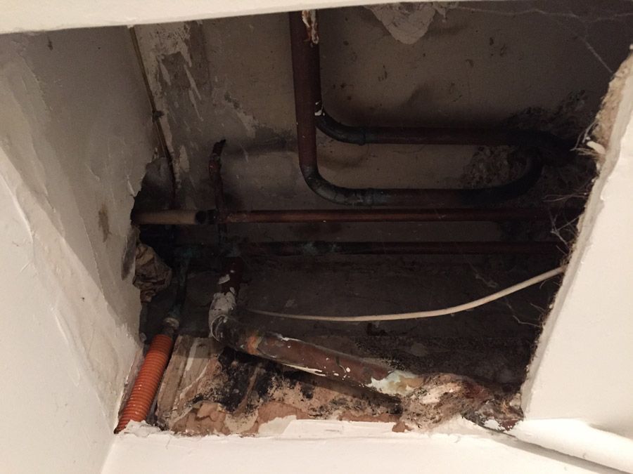 Un trou dans un mur avec des tuyaux qui en sortent