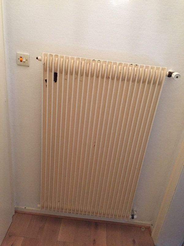 Un radiateur blanc est accroché sur un mur blanc dans une pièce.