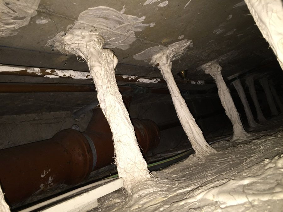 Une pièce très sombre avec beaucoup de tuyaux et beaucoup de mousse sur le sol.