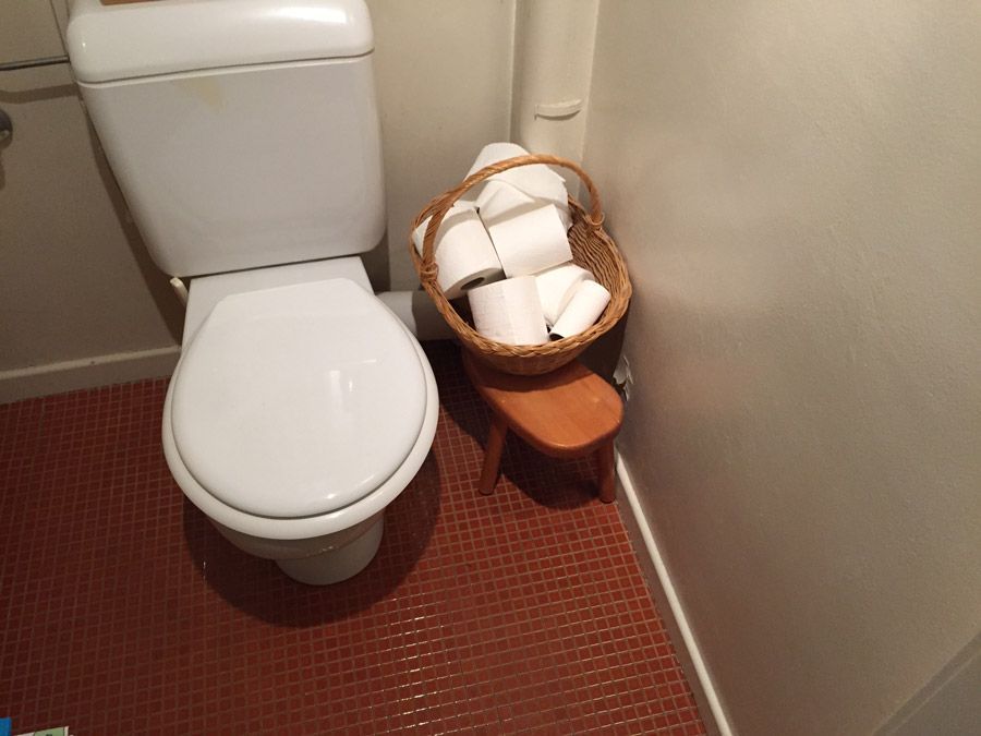 Des toilettes avec un panier de papier toilette à côté
