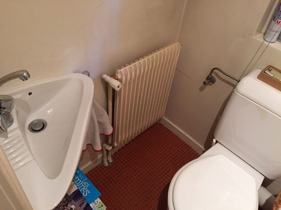 Une salle de bain avec WC, lavabo et radiateur.