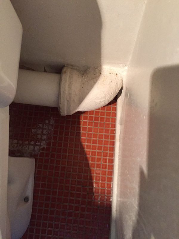 Une salle de bain avec toilettes, lavabo et sol en carrelage rouge.