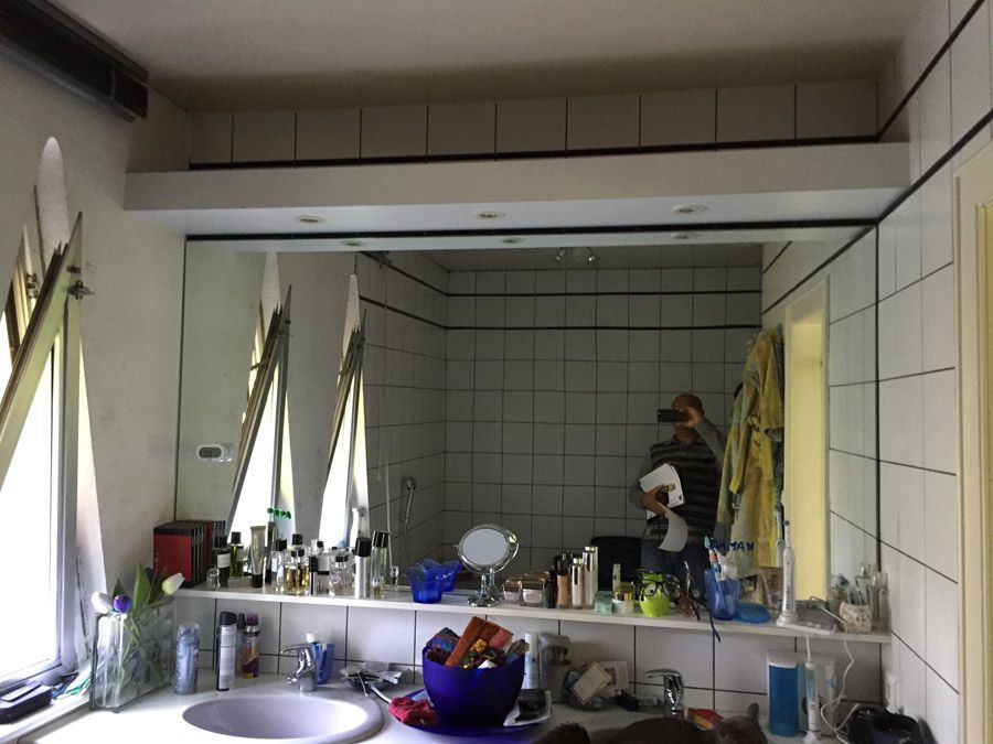 Une salle de bain avec un grand miroir et un lavabo.