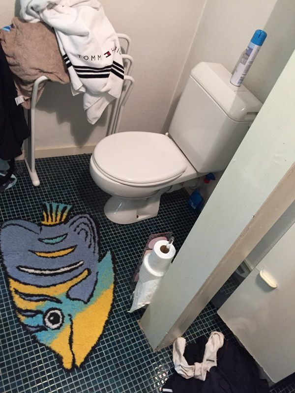 Une salle de bain avec des toilettes et un tapis qui ressemble à un poisson