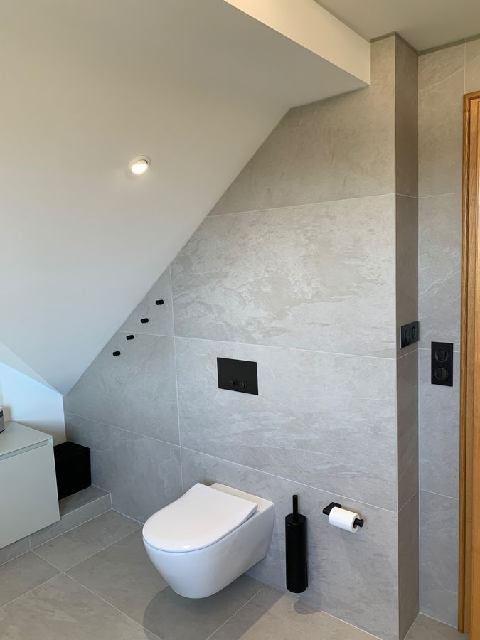 Une salle de bain avec WC et lavabo sous un escalier.