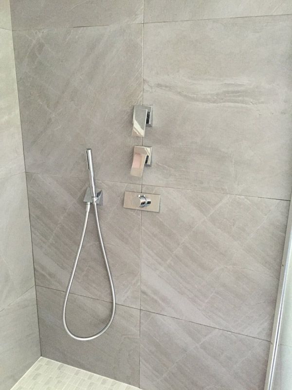 Une douche avec un tuyau fixé au mur.
