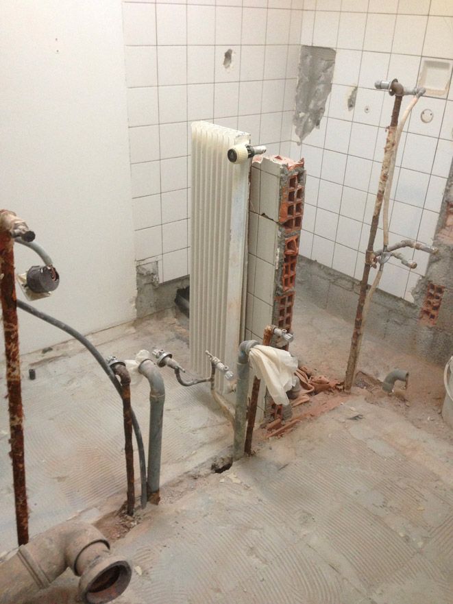 Une salle de bain en construction avec un radiateur et des tuyaux.