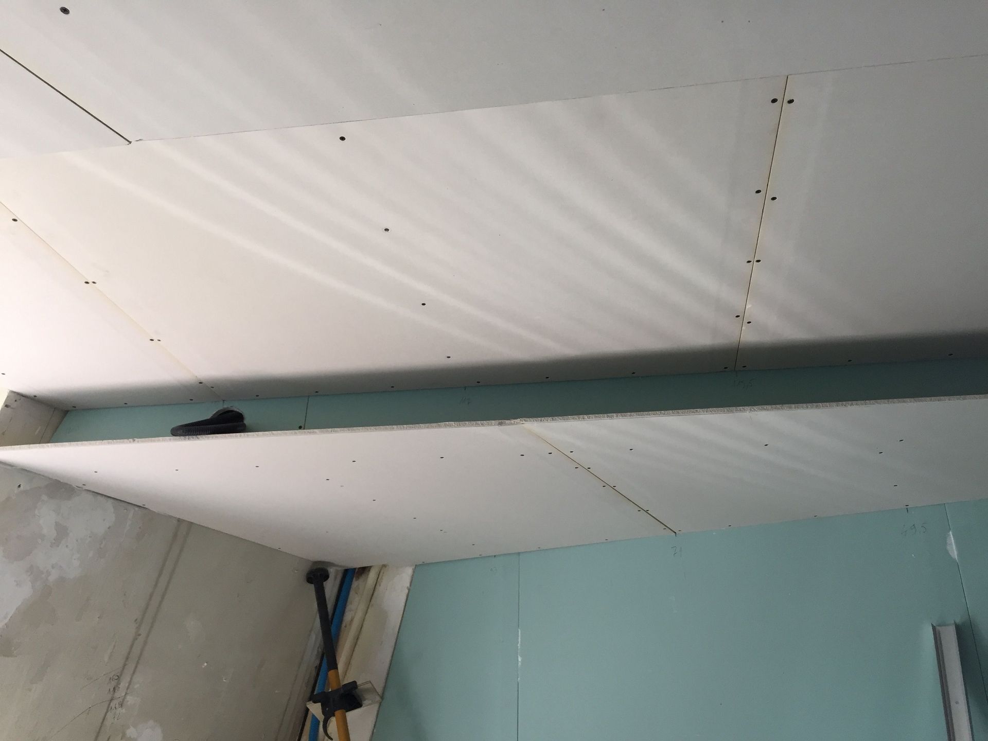 Un plafond est en cours de construction dans une pièce avec un mur bleu.