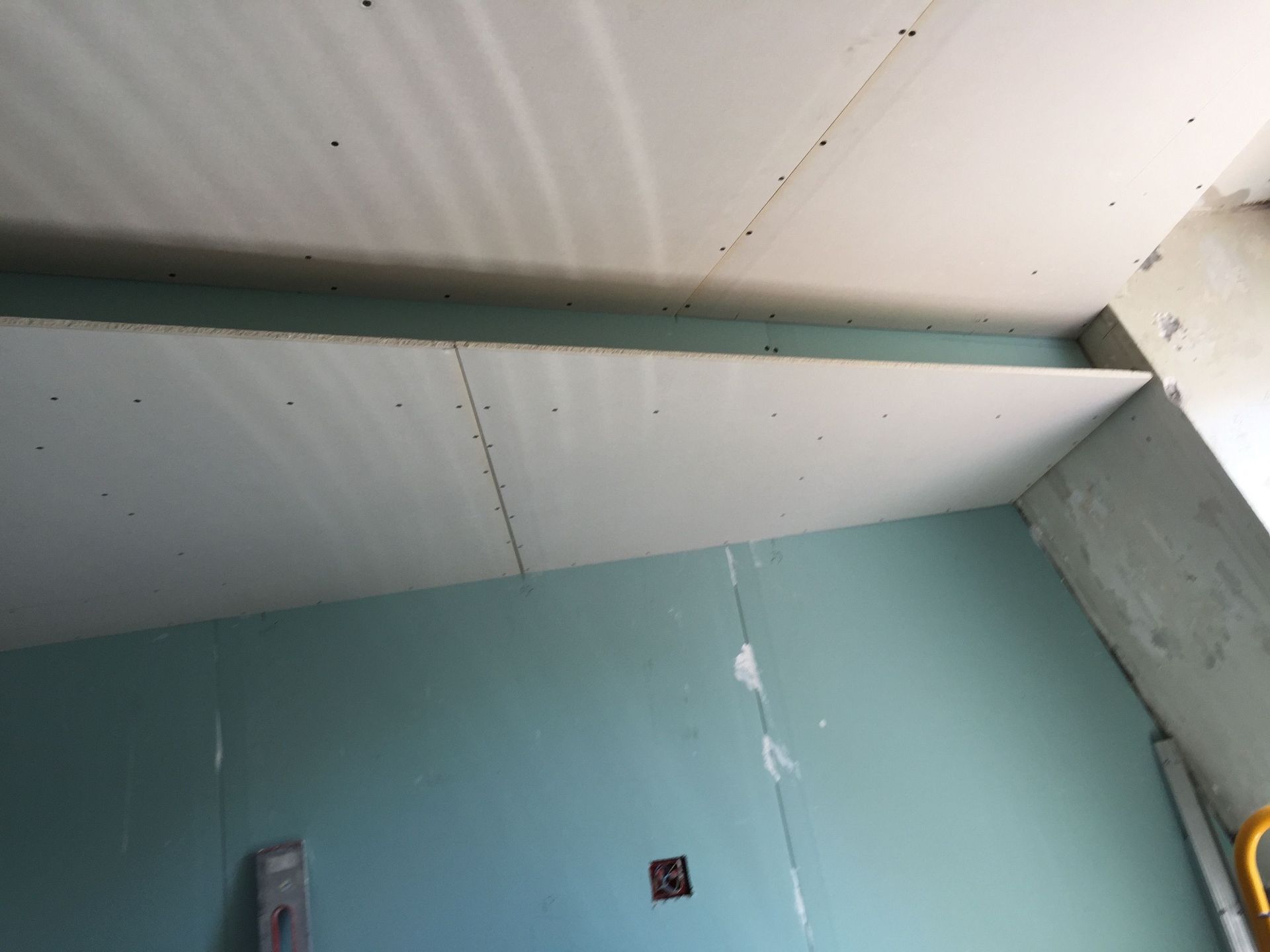 Une pièce avec un plafond en construction et un niveau sur le mur.