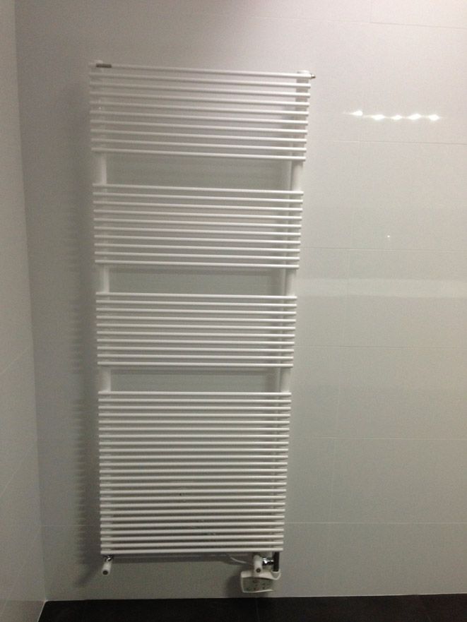 Un porte-serviettes blanc est accroché sur un mur blanc dans une salle de bain.