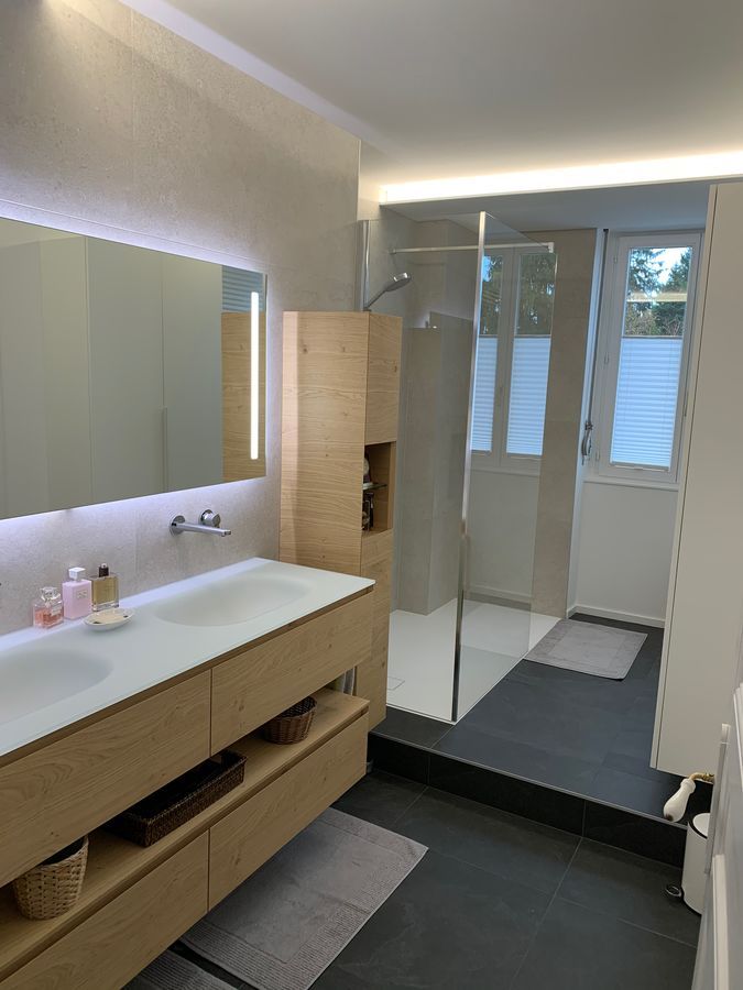 Une salle de bain avec lavabo, miroir et douche à l'italienne.