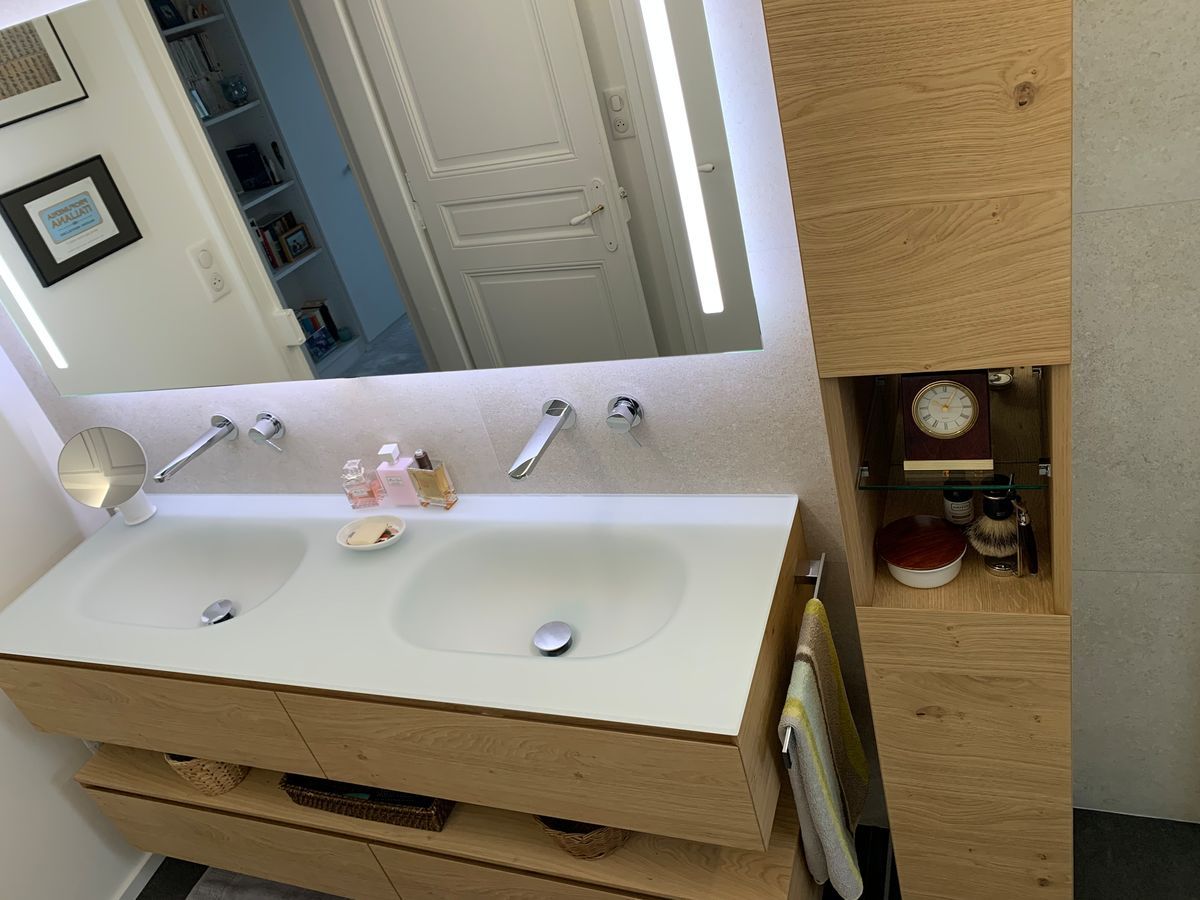 Une salle de bain avec deux lavabos, un miroir et une horloge.