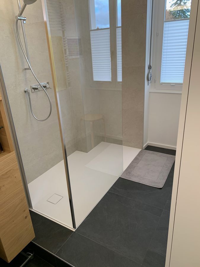 Une salle de bain avec douche à l'italienne et fenêtre.