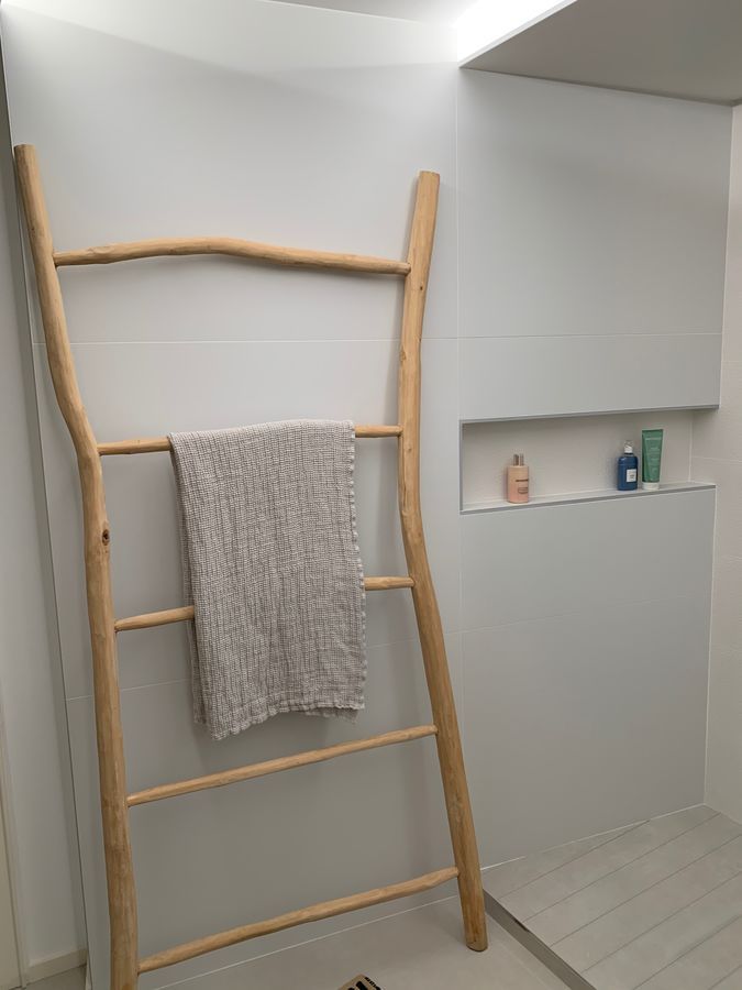 Une échelle en bois avec une serviette accrochée dessus dans une salle de bain.
