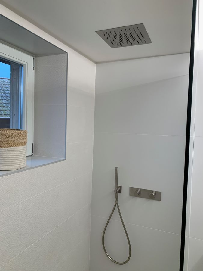 Une salle de bain avec pommeau de douche et fenêtre.