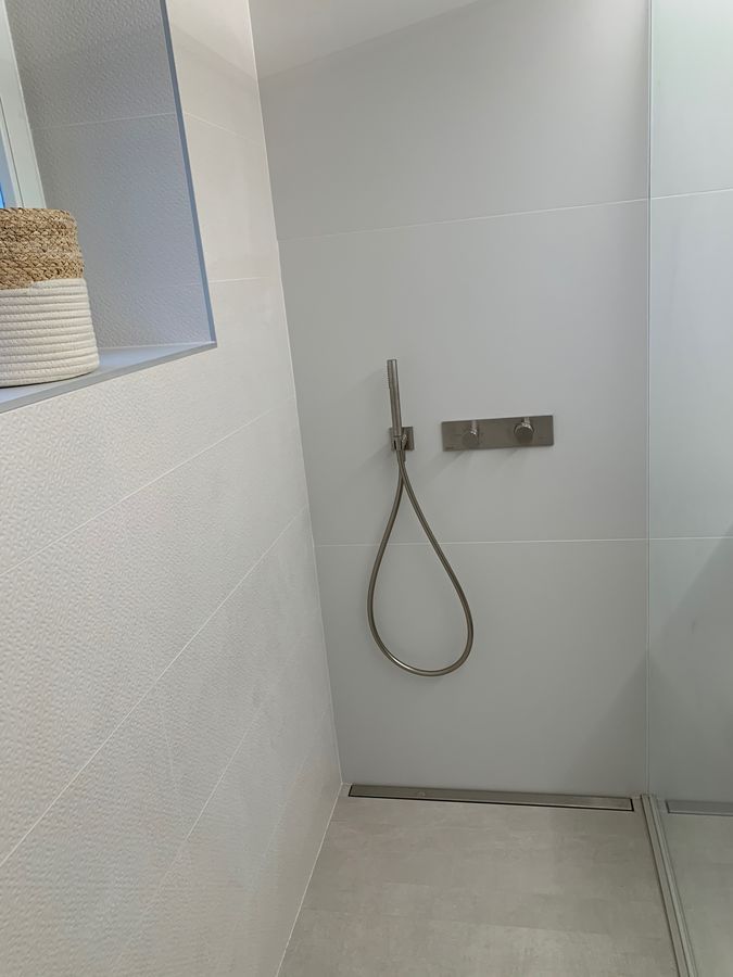 Il y a une douche avec un tuyau suspendu au mur.