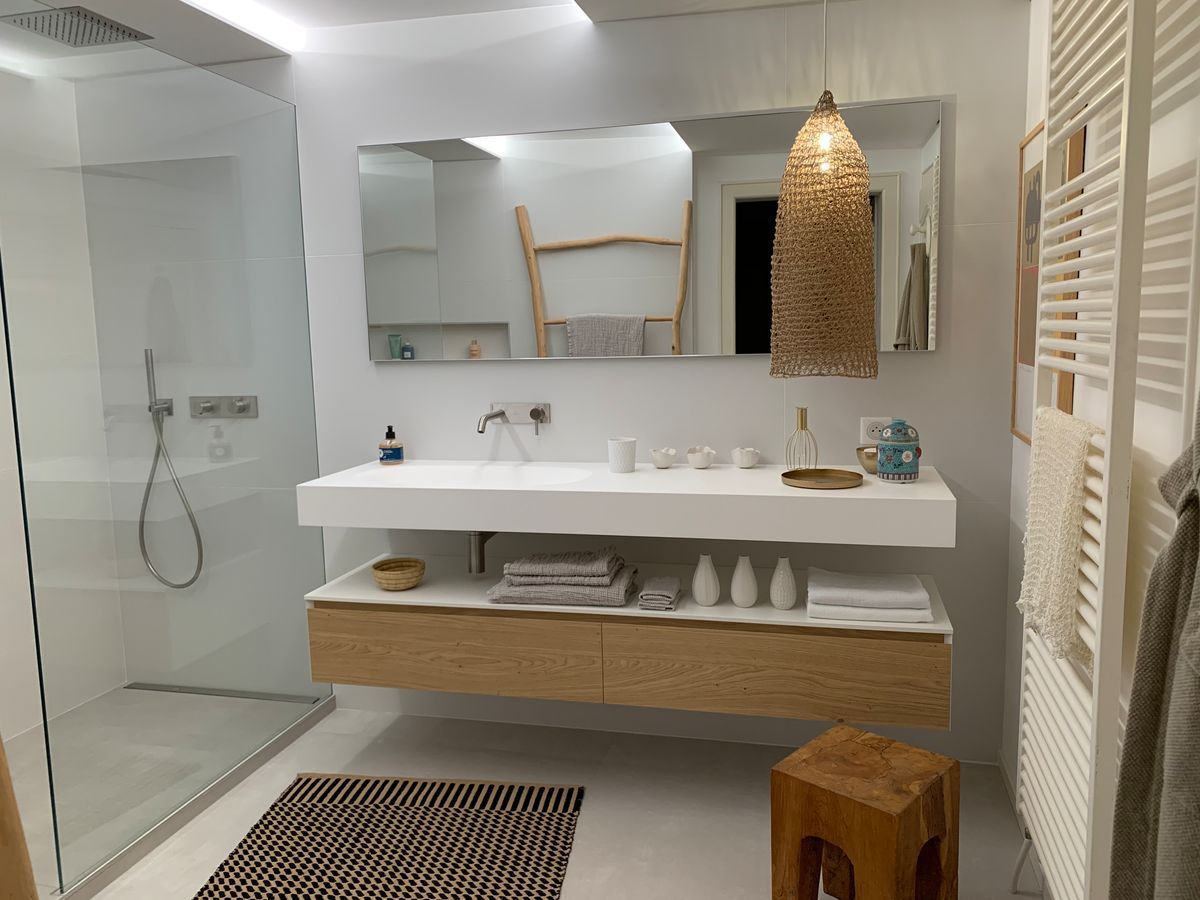 Une salle de bain avec deux lavabos, un miroir et un tabouret.