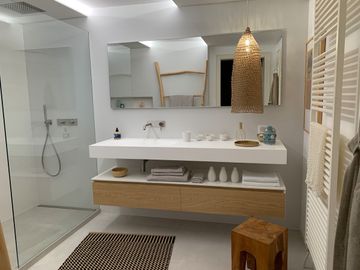 Une salle de bain avec deux lavabos, un miroir et un tabouret.