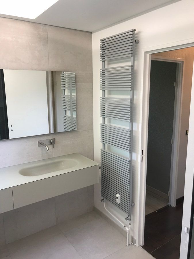 Une salle de bain avec un lavabo, un miroir et un porte-serviettes