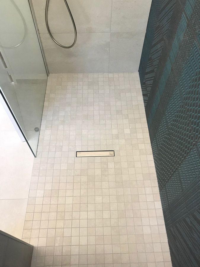 Une douche à l'italienne avec un sol carrelé et une pomme de douche.