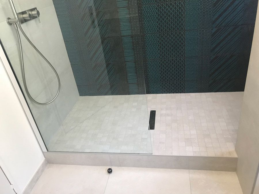 Une salle de bain avec douche à l'italienne et sol carrelé.