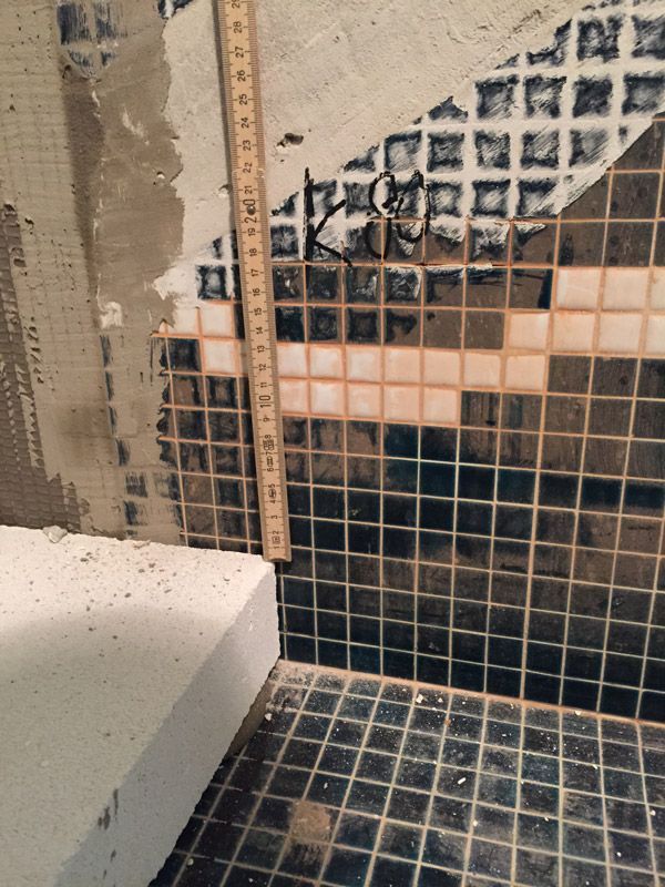 Une règle est posée sur un mur carrelé dans une salle de bain