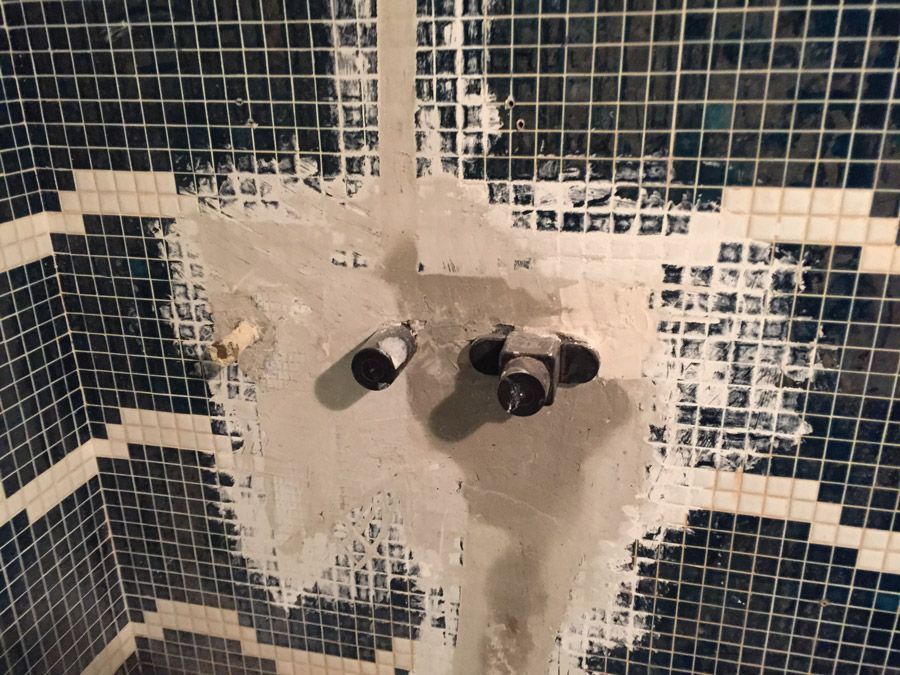 Un mur carrelé avec quelques robinets dessus