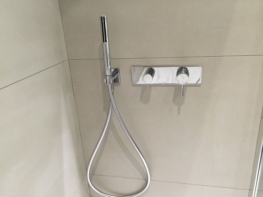 Une pomme de douche est fixée à un mur dans une salle de bain.