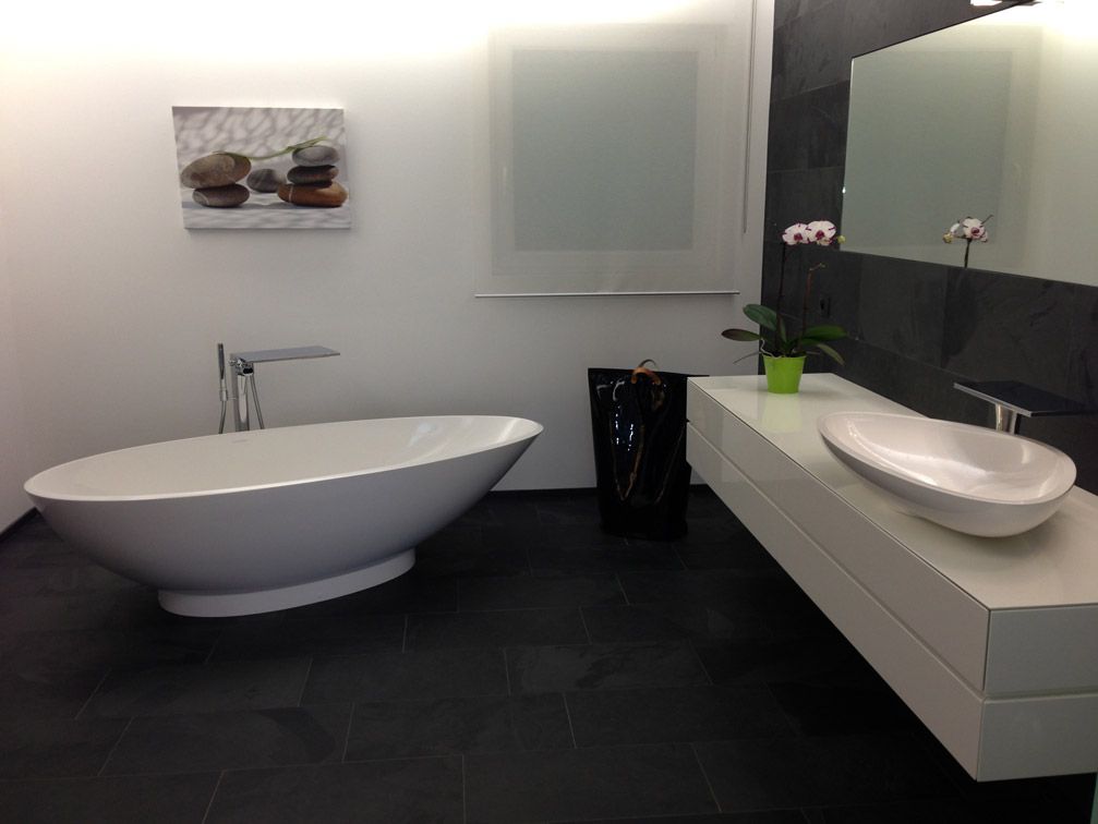 Salle de bain moderne avec une baignoire ovale blanche, une vanité blanche flottante et un sol en carrelage noir.