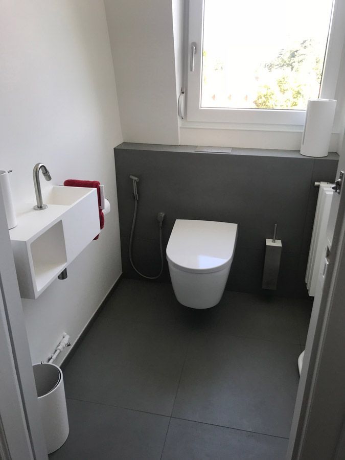 Une salle de bain avec toilettes, lavabo et fenêtre