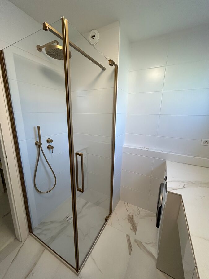 Une salle de bain avec douche et machine à laver