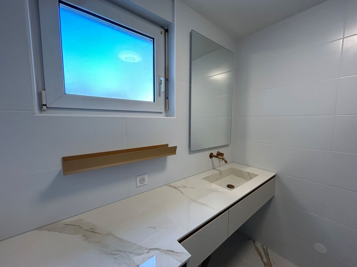 Une salle de bain avec un lavabo, un miroir et une fenêtre