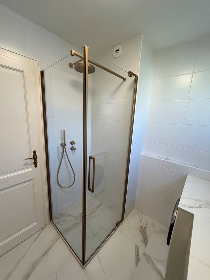 Une salle de bain avec une cabine de douche et un pommeau de douche.