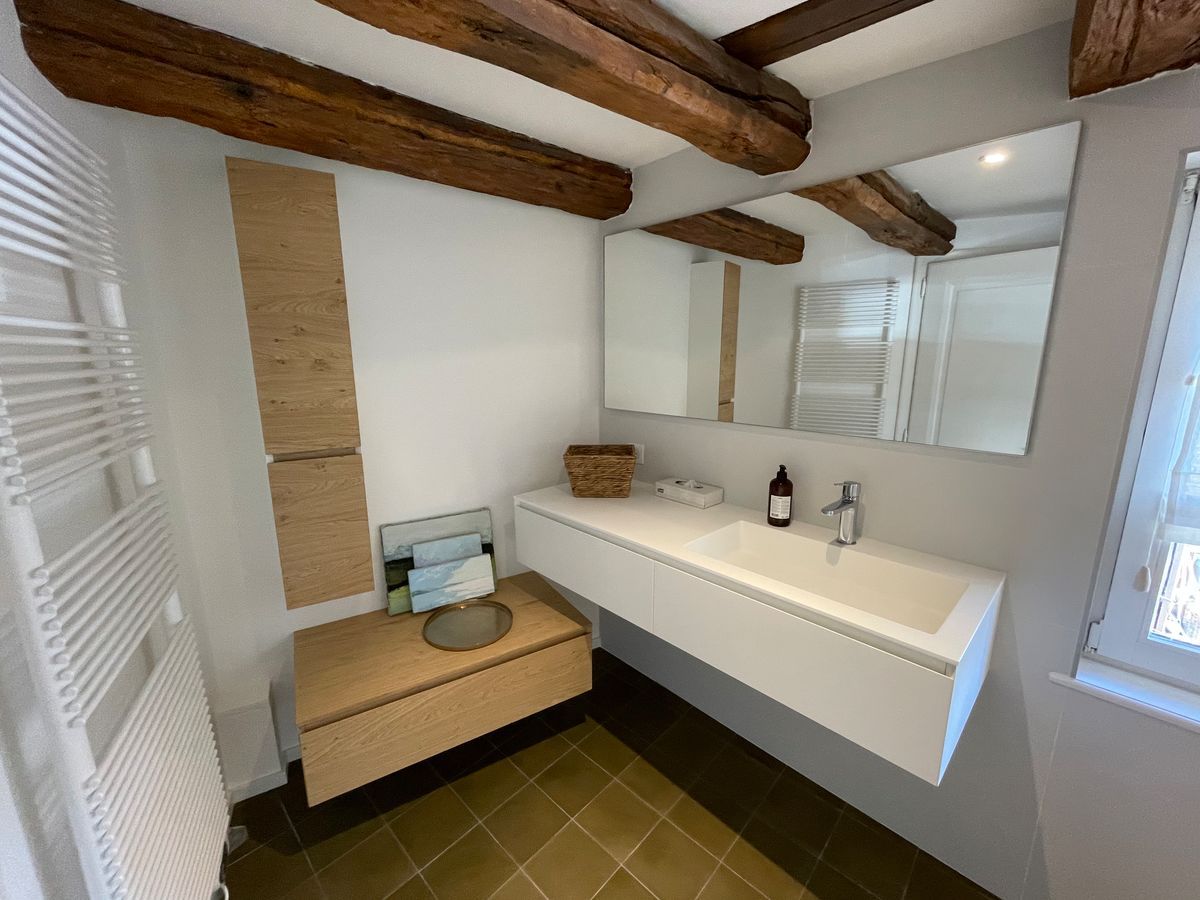 Une salle de bain avec lavabo, miroir et porte-serviettes.