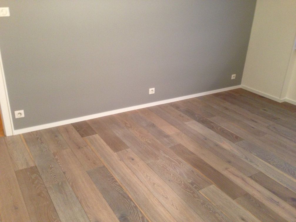 Une pièce avec un plancher en bois et un mur gris.
