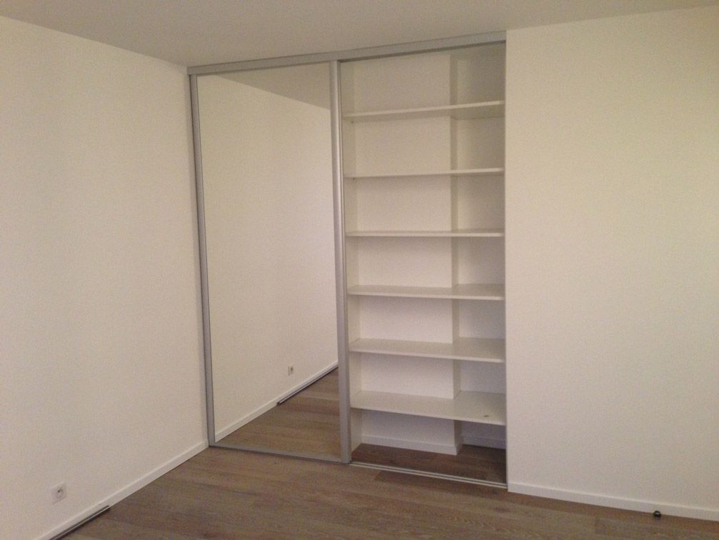 Une chambre avec une porte coulissante en verre et des étagères.