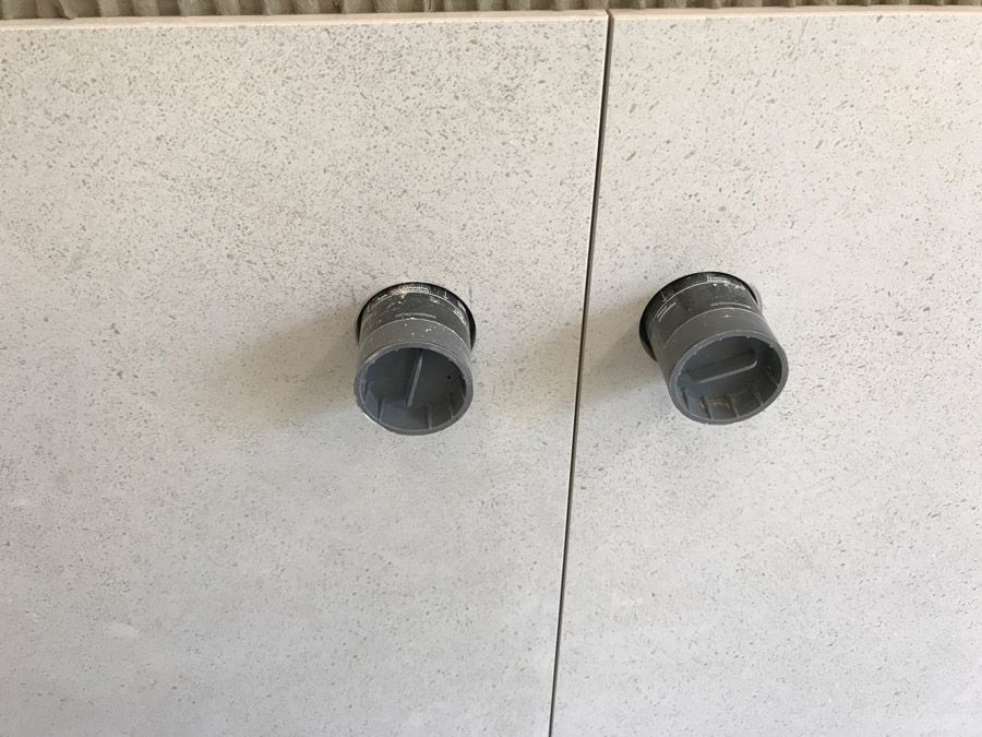 Deux tuyaux gris sont posés sur un mur blanc.