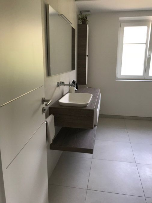 Une salle de bain avec un lavabo, un miroir et une fenêtre.