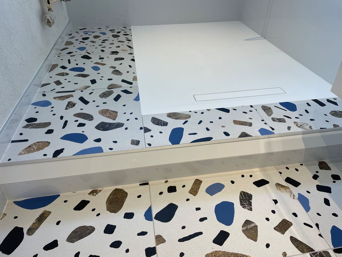 Une salle de bain avec un sol en terrazzo et une cabine de douche