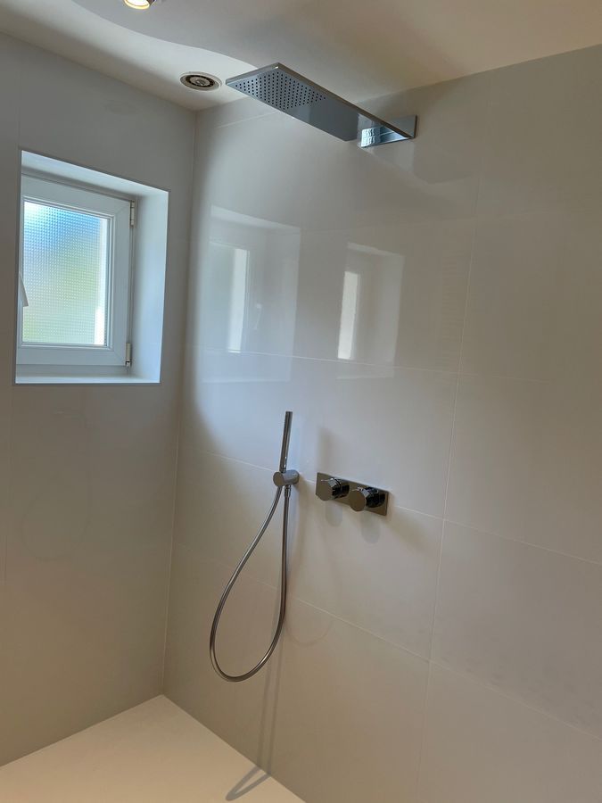 Une salle de bain avec pommeau de douche et fenêtre.