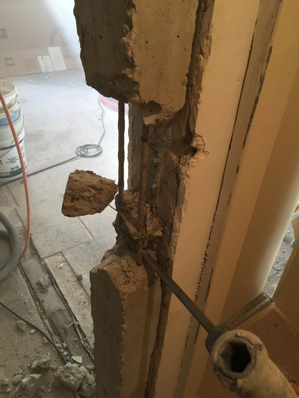 Une personne découpe un trou dans un mur avec un marteau