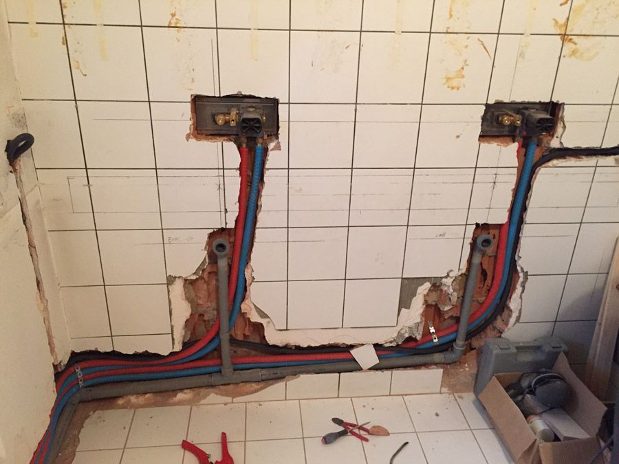 Une salle de bain avec beaucoup de tuyaux sortant du mur
