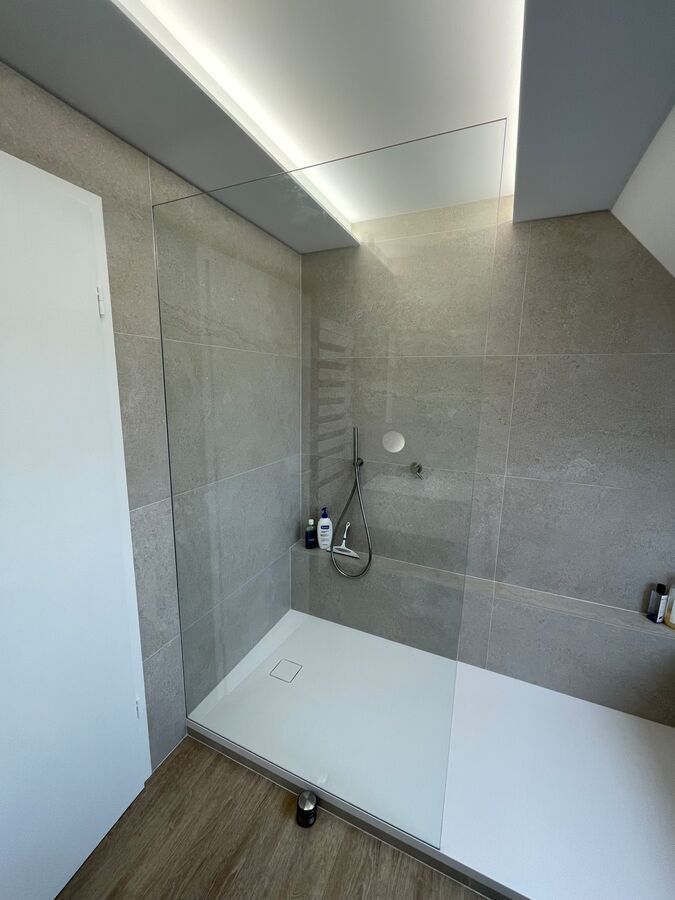 Une salle de bain avec une douche à l'italienne et une porte vitrée.