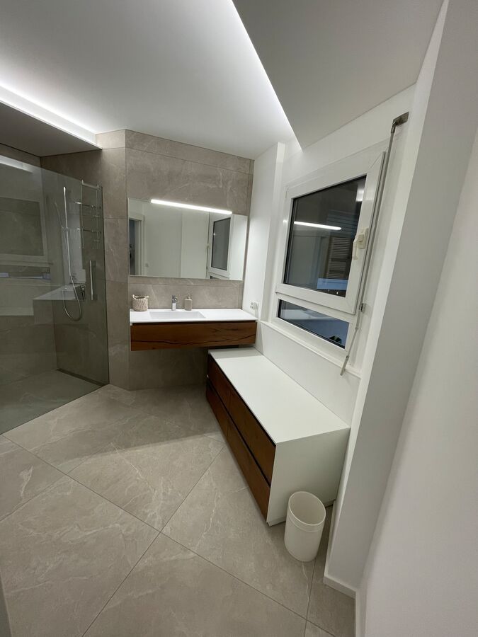 Une salle de bain avec un lavabo, un miroir et une fenêtre.