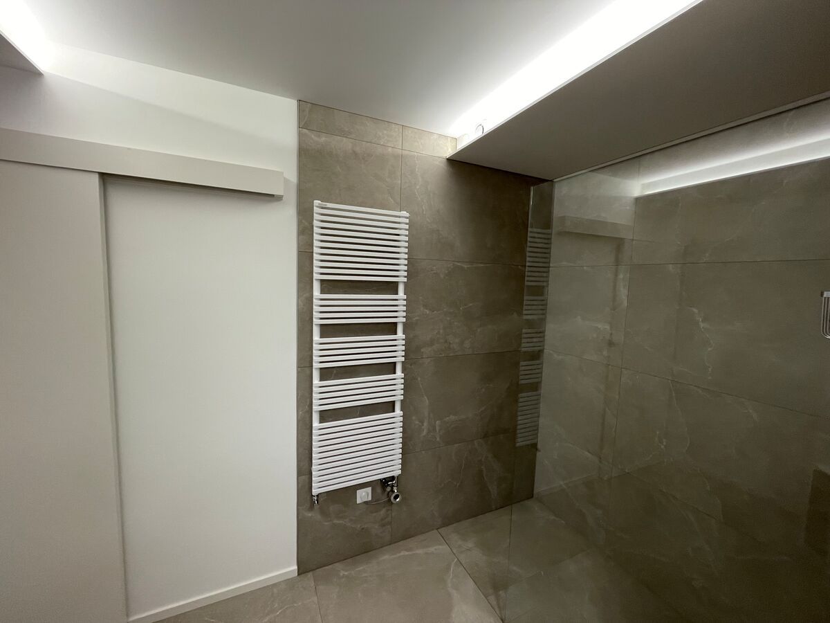 Une salle de bain avec une porte coulissante en verre et un porte-serviettes au mur.