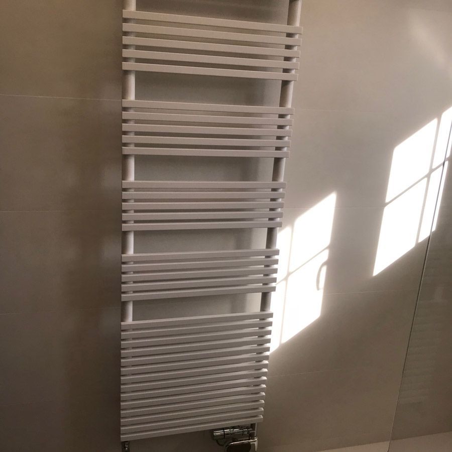 Un porte-serviettes blanc est accroché au mur d'une salle de bain.