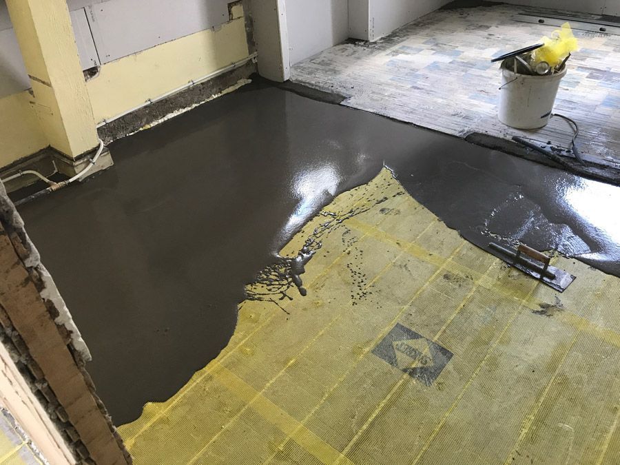 Un seau de ciment est versé sur un sol carrelé.