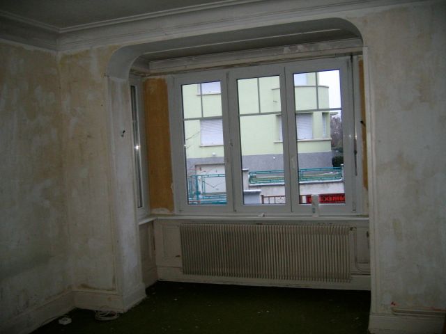 Une pièce vide avec une grande fenêtre et des radiateurs