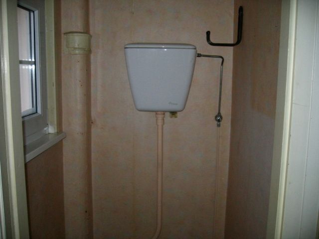 Des toilettes dans une salle de bain à côté d'une fenêtre